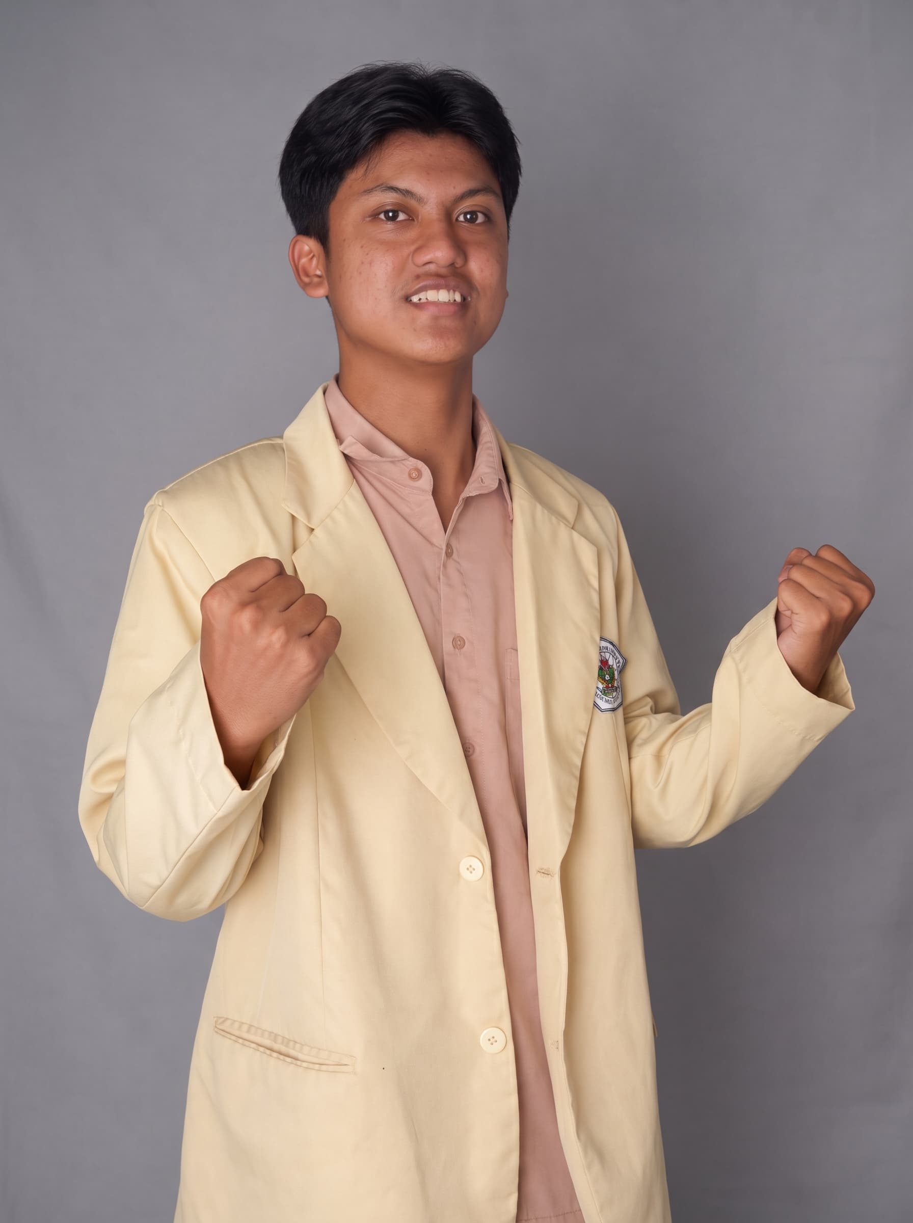M. Nadiril Khoir smiling in a cream blazer against a grey studio backdrop